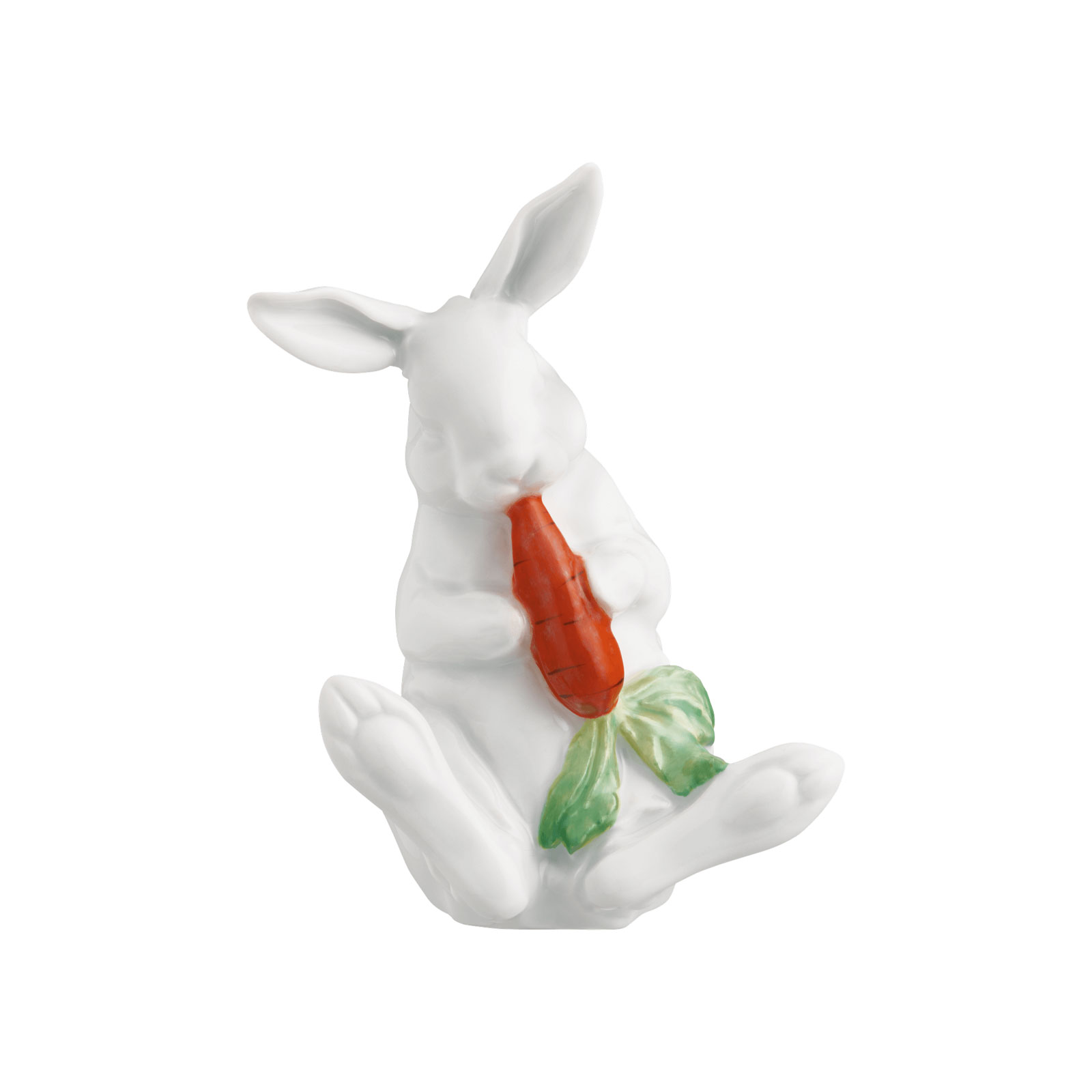 Ein weißer Porzellanhase mit aufgestellten Ohren, der sitzend eine orangene Karotte in den Vorderpfoten hält und sie knabbert.