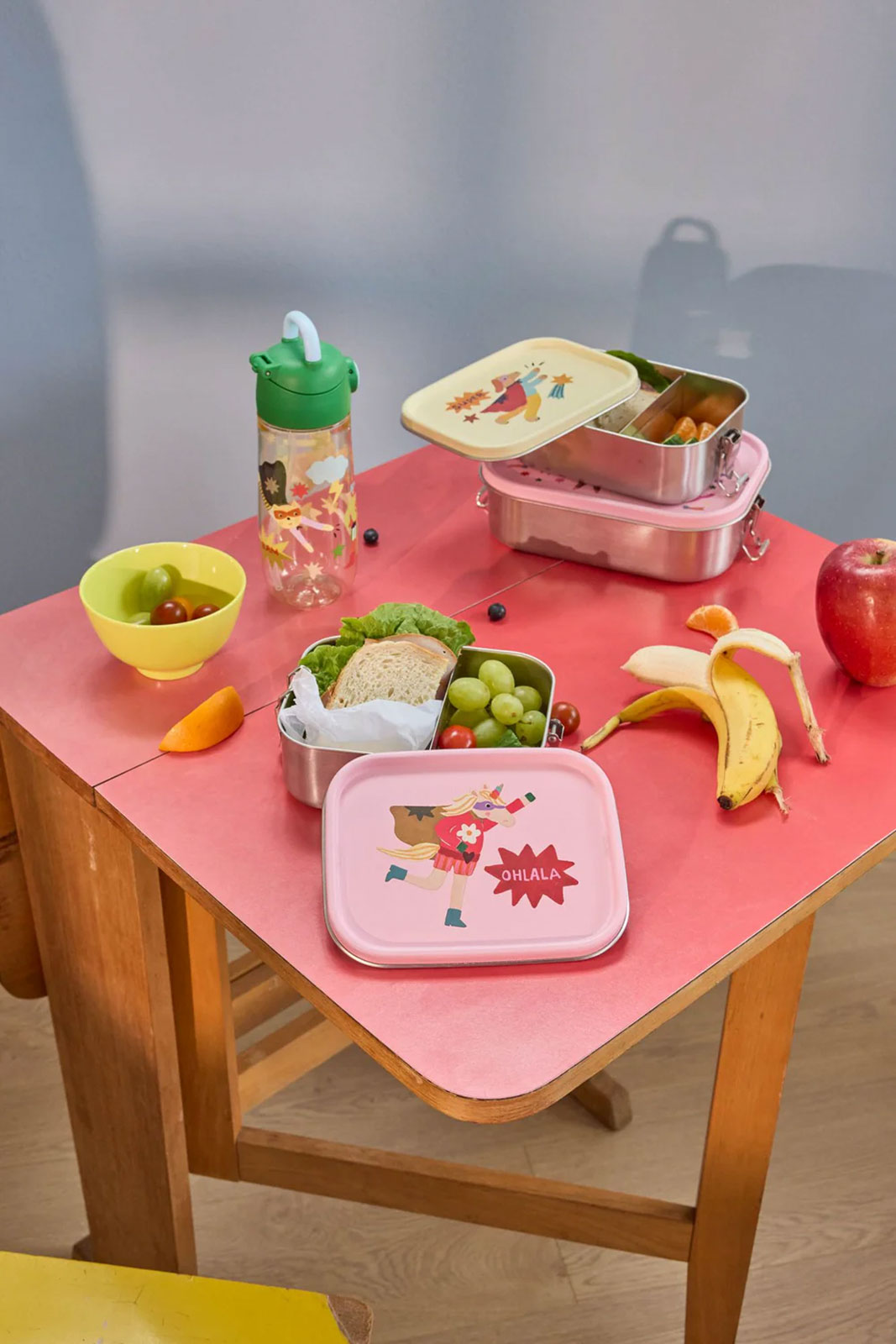 Einige Hero Print Bordosen sind ausgebreitet auf einem pinken Tisch für ein leckeres Picknick.