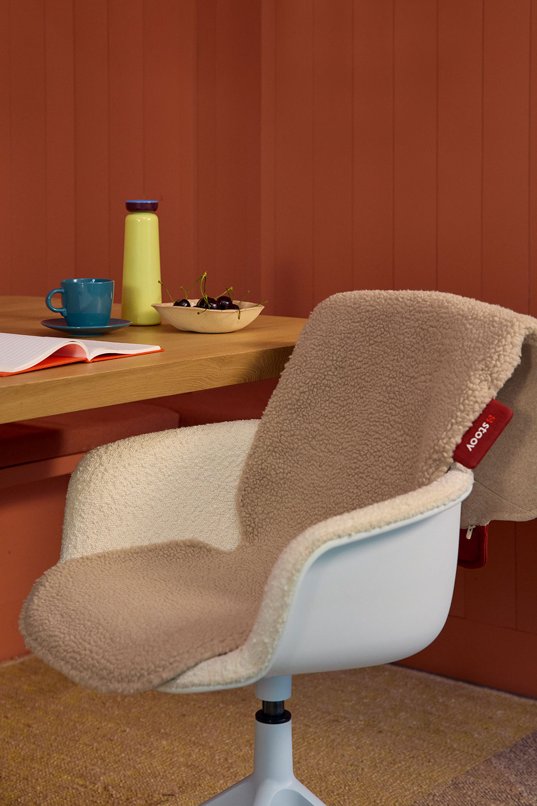 Ein weißer, schalenförmiger Bürostuhl wird mit einer Big Hug Heizdecke Woolly Beige von Stoov kuscheliger gemacht.