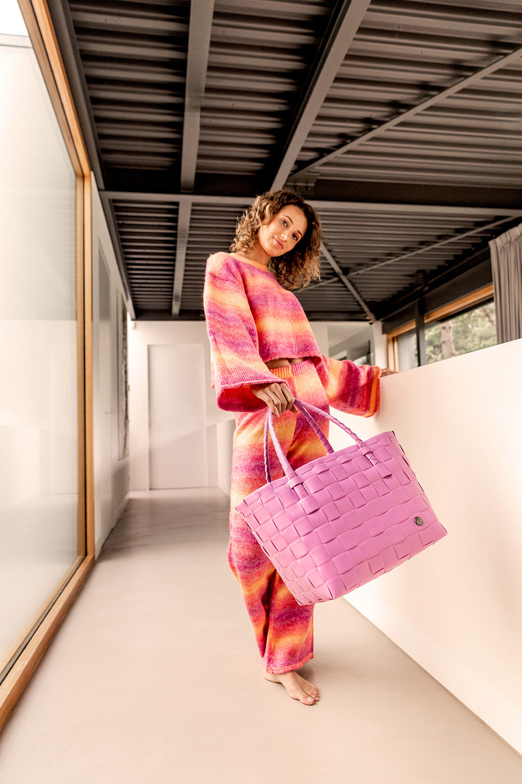 Eine Frau im rosa-roten Outfit schwingt den Paris Shopper fuchsia pink der Kamera entgegen.