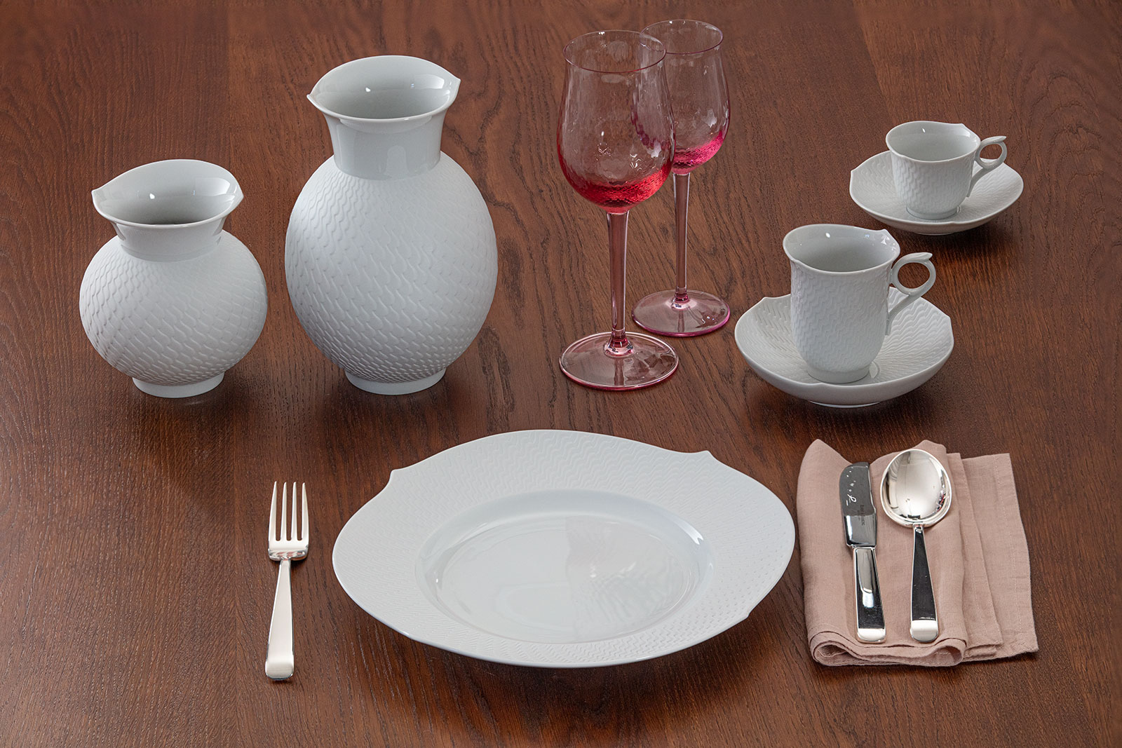 Auf einem dunklen Holztisch steht ein Gedeck der Serie Wellenspiel Relief von Meissen. Die Kaffeetasse läd ein auf ein energiespendendes Getränk.