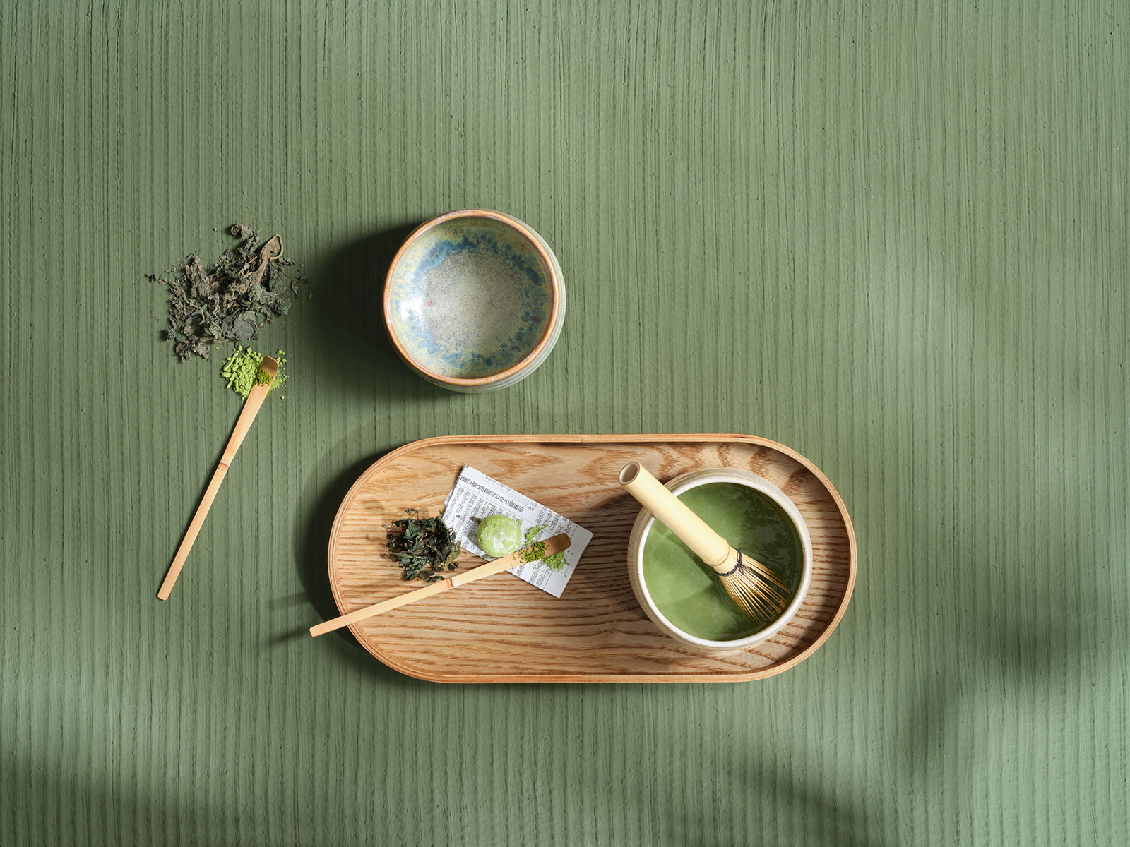 Draufsicht auf ein Stillleben der Matcha-Zubereitung mit Besen, Löffel und speziellen Schalen aus der Moribana Serie von Asa Selection.