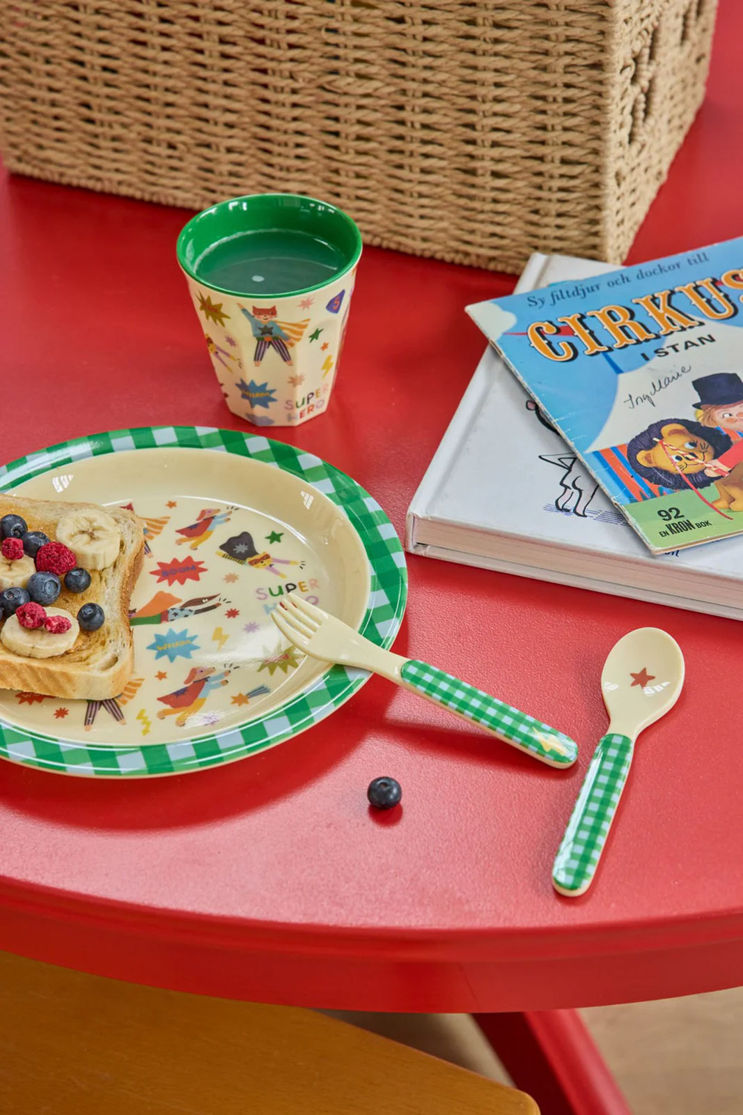 Auf einem roten Tisch steht das Hero Print Kindergeschirr in grün von Rice.