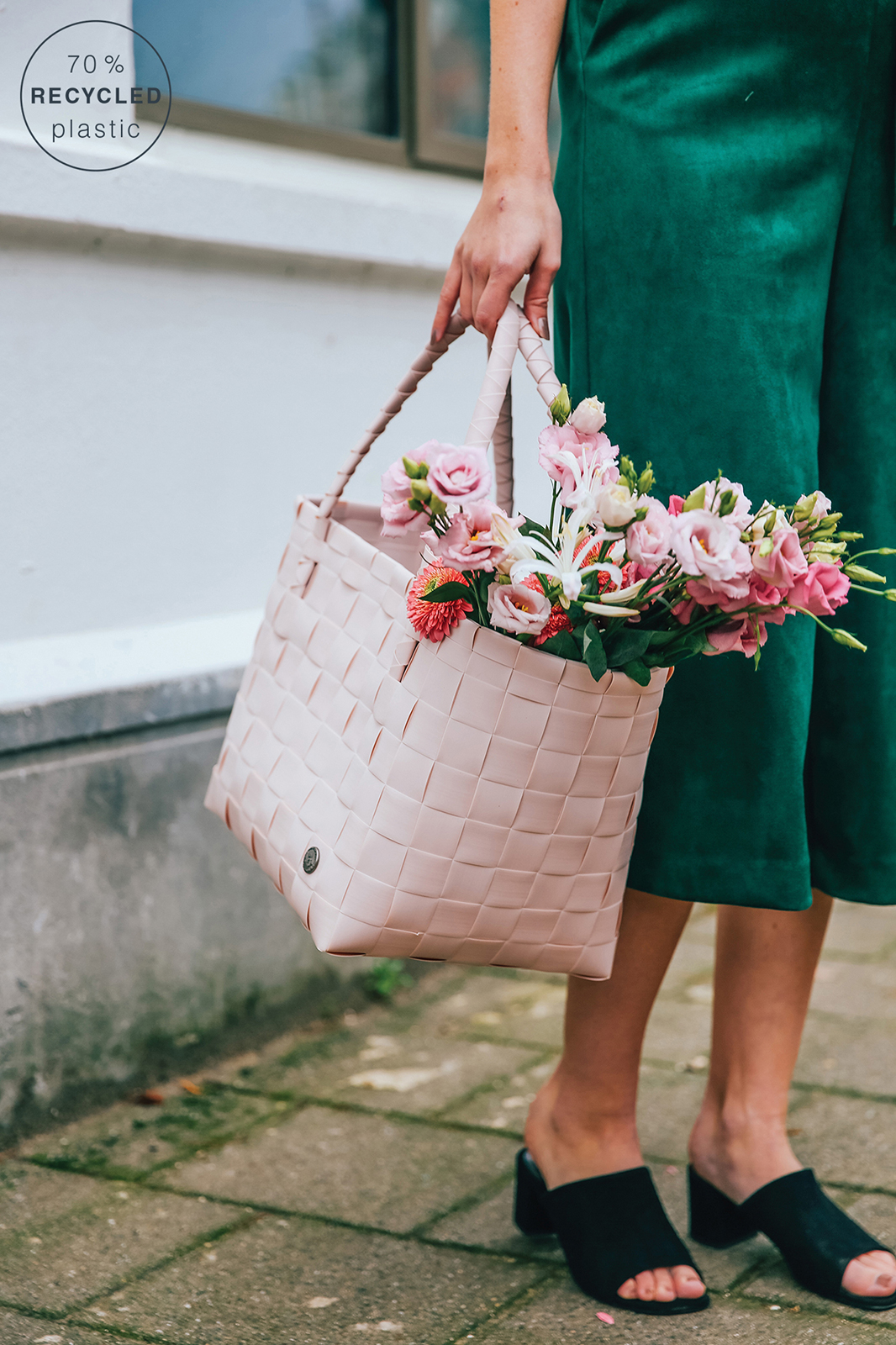 Eine Frau hält den rosafarbenen Paris Shopper auf dem Weg nach Hause vom Einkauf. Er überquillt mit frischen Blumen.