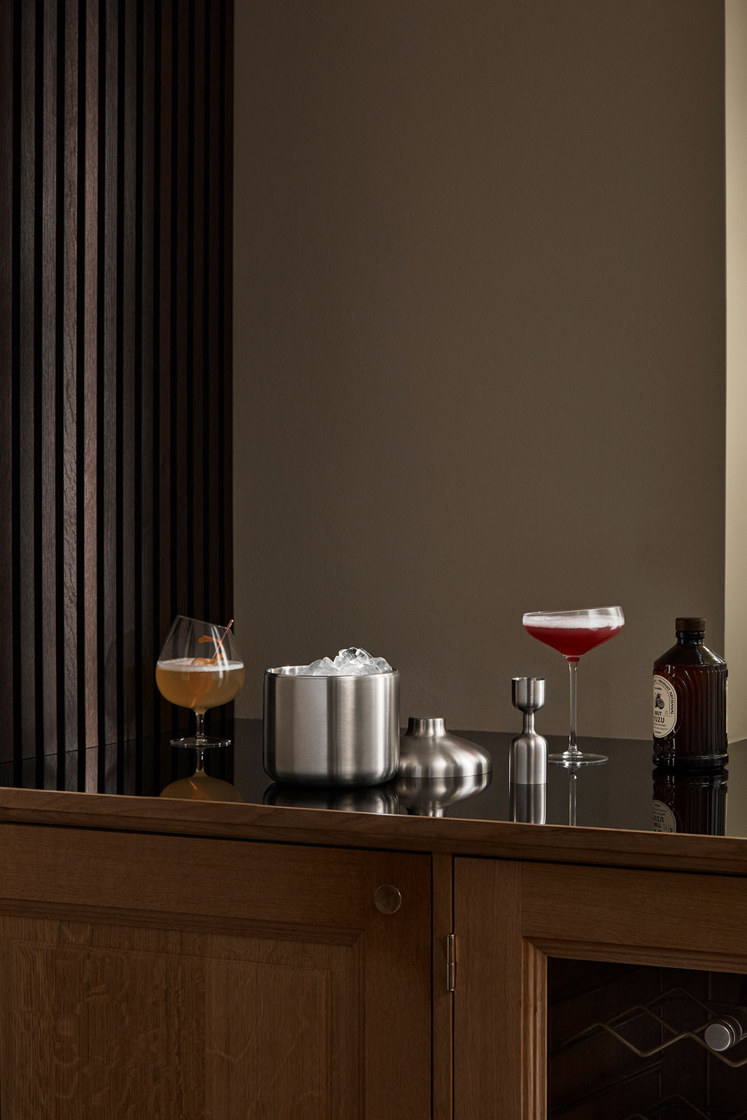 Ein Sideboard, auf dem ein Cocktailglas sowie die Produkte der Eva Trio Liquid Lounge Serie sind.