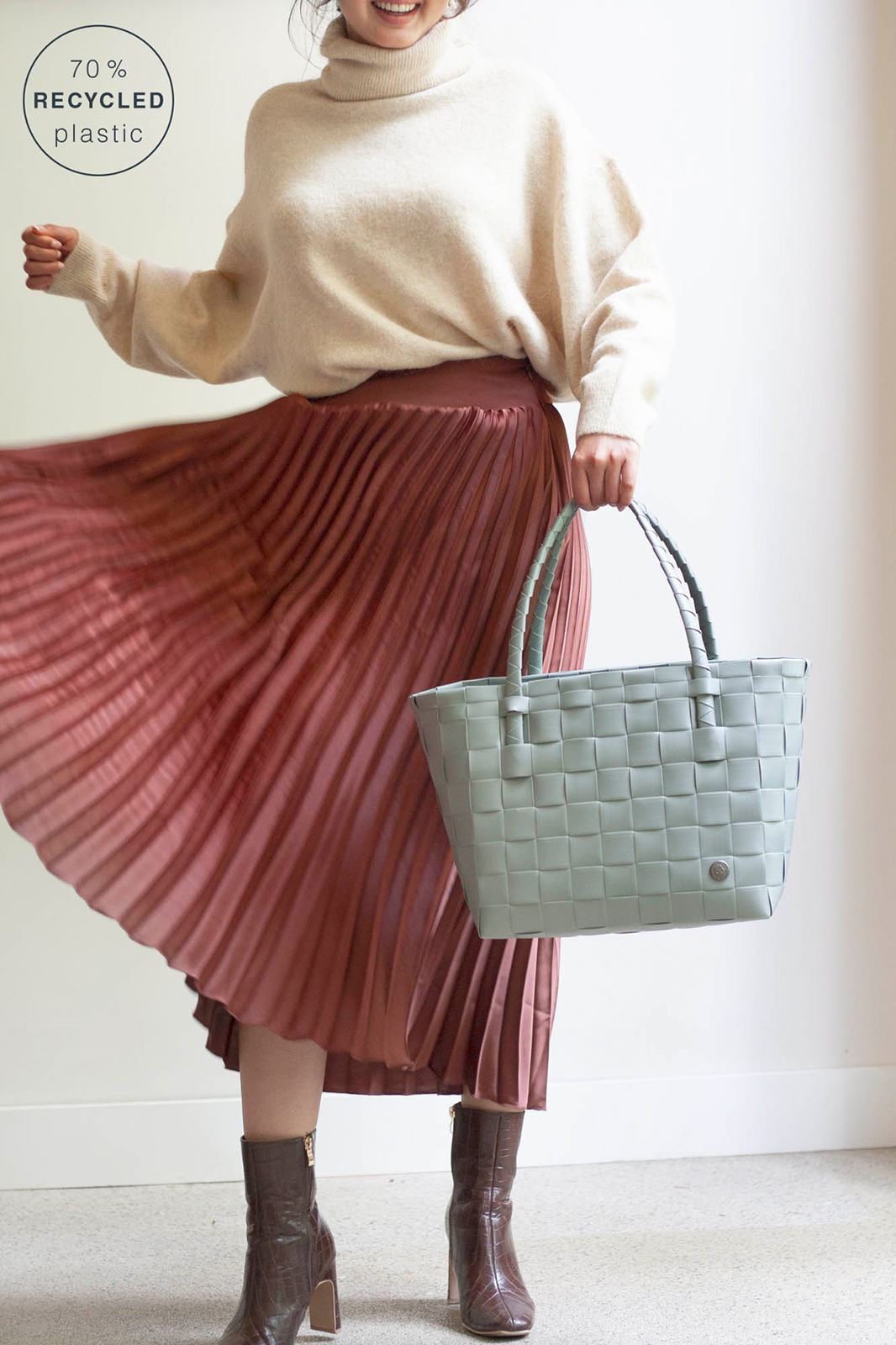 Eine Frau in einem lässig-eleganten Outfit trägt den salbeigrünen Paris Shopper. Er ist ein elegantes Accessoire.